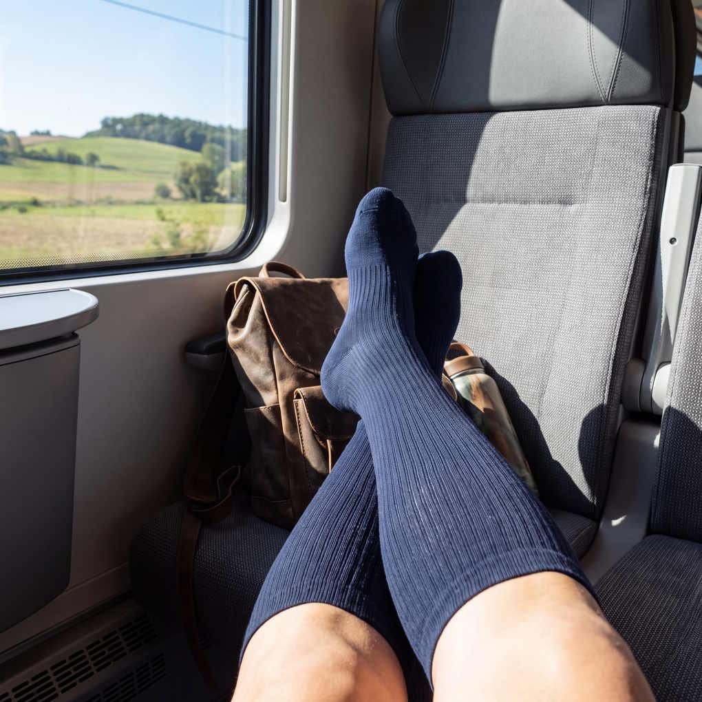 What are Compression Socks - A Traveler's Legs Wearing Navy Blue Compression Socks While Resting on a Train Journey | The List Of
